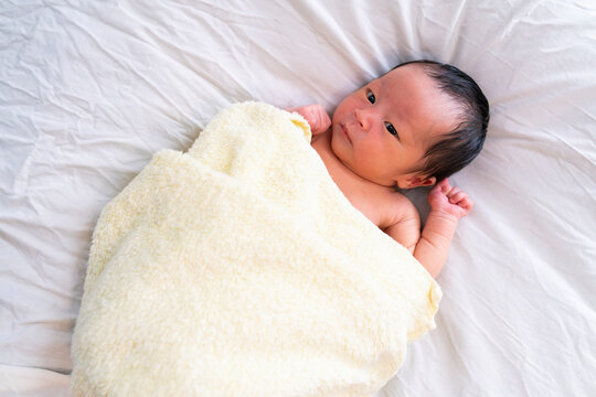 新生児がタオルにくるまれた写真