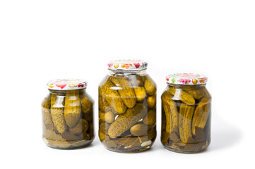 Fresh canned cucumbers in three jars, hermetically sealed with metal lids.