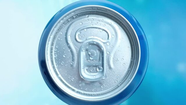 a man's hand takes a cold beer or a can of soda with drops of water. Drink drinks in aluminum cans with a latch. View from above. blue iridescent screen background