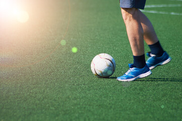 The ball and feet of a soccer player on the green surface of the stadium. game situation. Sunshine. Selective focus. Motion blur.
