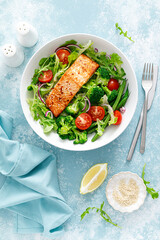 Grilled salmon fish fillet and fresh tomato vegetable salad with lettuce, arugula, broccoli and green beans. Healthy food, mediterranean diet