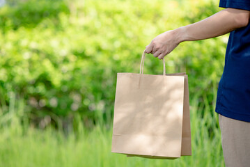 Hand holding paper bags that are environmentally friendly, reduce or reuse instead of using plastic bags.