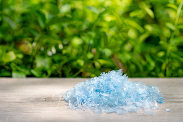 A Pile of PET bottle flakes with green tree blur background