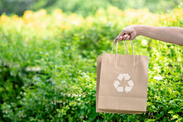 Hand holding paper bags that are environmentally friendly with recycle symbol, reduce or reuse instead of using plastic bags.