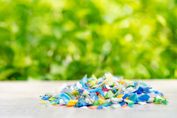 Fototapeta na wymiar A Pile of PET bottle flakes, Plastic bottle crushed, Small pieces of cut colorful plastic bottles with green blurred background