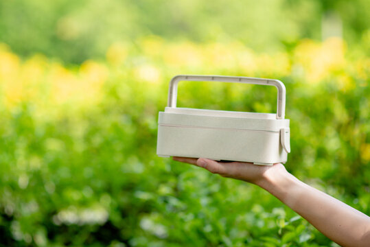 Hand holding Reusable food box with green blurred background.Reduce,Reuse,Zero Waste concept.