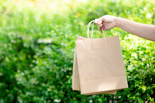 Hand holding paper bags that are environmentally friendly, reduce or reuse instead of using plastic bags.
