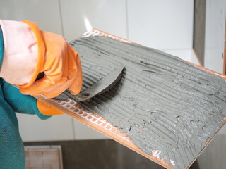 Laying tiles on the wall.