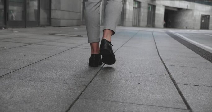 Rear back view feet of businessman commuting to work. Confident guy in leather shoes and suit being on his way to office building