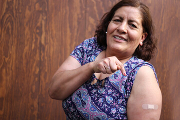 Hispanic old woman shows her arm recently vaccinated against Covid-19 in the new normal for the...