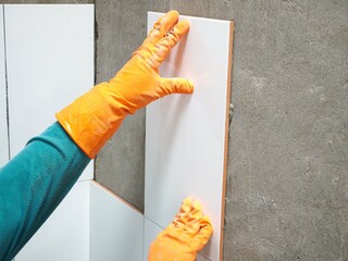 Laying tiles on the wall. Worker installing big ceramic tiles on the walls.
