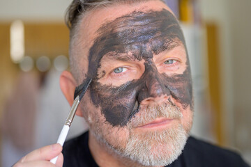 Man in his fifties applying a face mask