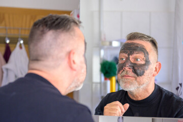 Man checking out his face mask in a bathroom mirror
