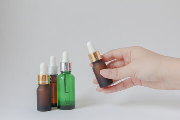 Woman hands holding facial essential oil or serum packaging on white background. Beauty cosmetic product for skincare concept.