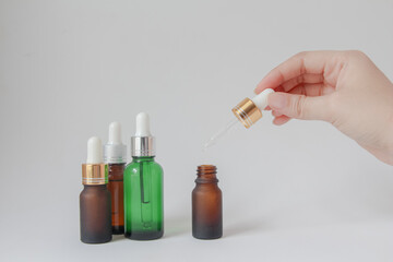 Woman hands holding facial essential oil or serum packaging on white background. Beauty cosmetic product for skincare concept.