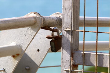 An iron padlock hangs on a closed gate