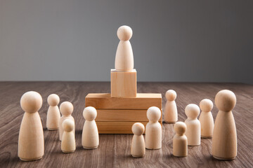  Wooden people figures on top of wooden blocks. Career growth, development and leadership