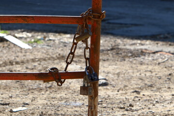 An iron padlock hangs on a closed gate
