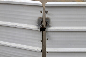 An iron padlock hangs on a closed gate