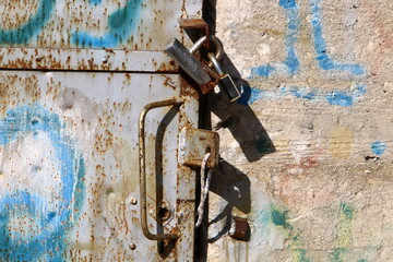 An iron padlock hangs on a closed gate