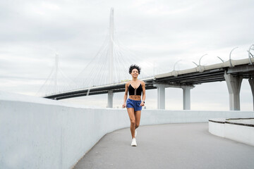 A female athletic runner is running doing workout exercises outside, a smart watch on her hand.