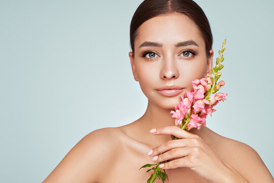 Portrait Beautiful Young Woman With Clean Fresh Skin. Model With Healthy Skin, Close Up Portrait. Cosmetology, Beauty And Spa. Girl With A Pink  Flower