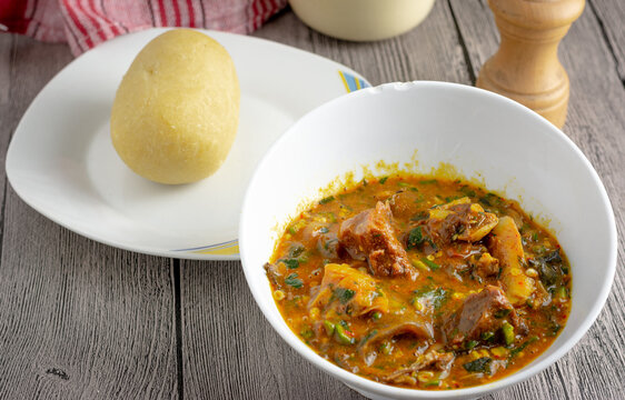 Ogbono soup a Nigerian traditional delicacy with beef in white bowl served with molded garri or Eba ready to eat