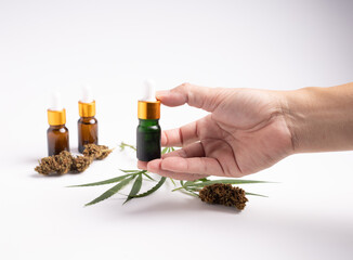 hand hold the marijuana extract oil with a backdrop with a leaf and flower