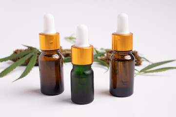 Various glass bottles with CBD oil, THC tincture and hemp leaves on a white background.