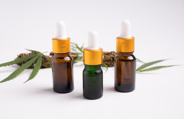 Various glass bottles with CBD oil, THC tincture and hemp leaves on a white background.
