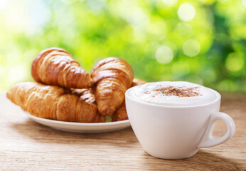 Cup of cappuccino coffee and croissants