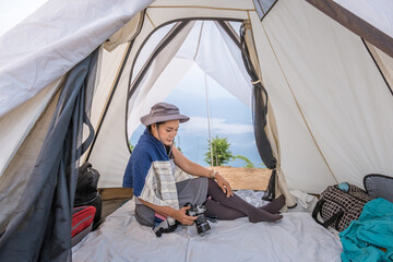 Woman sitting in the tent and looking photo in the camera. View from inside
