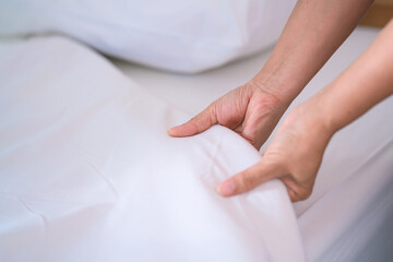 Female Hand set up white bed sheet in bedroom or maid hands making bed in a hotel room - 514589535