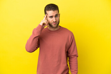 Handsome blonde man over isolated yellow background thinking an idea