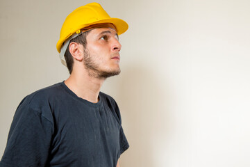 Worker with yellow safety hat for construction site work. Young white caucasian man with short hair and dark eyes.