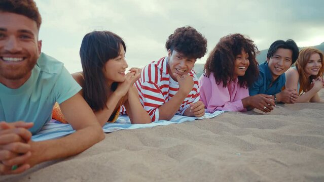 roup of friends having fun on the beach. Multiethnic Teenagers having a good time during the summer celebrating together next to the ocean.