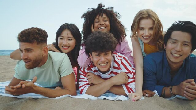 Group of friends having fun on the beach. Multiethnic Teenagers having a good time during the summer celebrating together next to the ocean.