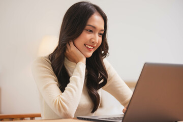 Asian girl using computer laptop playing game and social media or chatting with her friends.