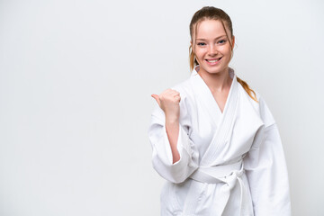 Young caucasian girl doing karate isolated on white background pointing to the side to present a...