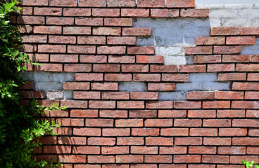 Fototapeta premium The Old Cracked Wall of a concrete building. A part of the red brick wall was abandoned.