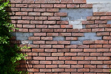 The Old Cracked Wall of a concrete building. A part of the red brick wall was abandoned.