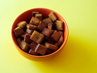 Salted croutons in a bowl on a yellow background