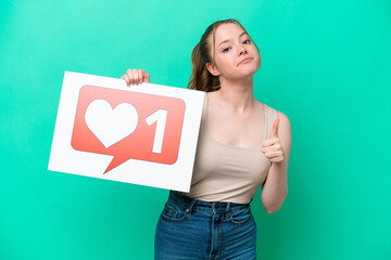 Young caucasian woman isolated on green background holding a placard with Like icon with thumb up