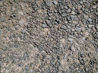 A dirt road made of cinder stones, viewed from above in the rays of the midday sun.