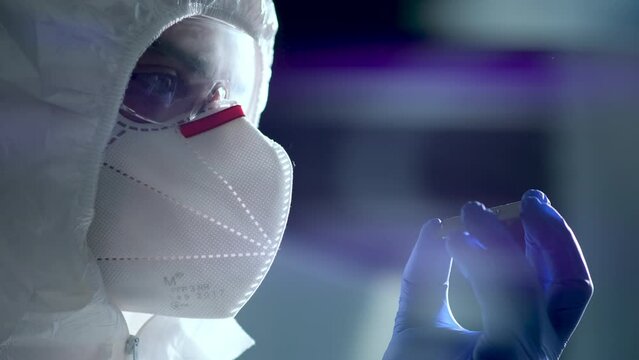 The concept of computer technology: An engineer in a sterile jumpsuit holds a computer microchip in his gloves and examines it. The concept of artificial intelligence