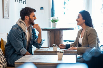 Young lovely couple talking and laughing while drinking coffee together in healthy coffee shop.