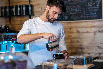 Handsome young waiter preparing natural coffee to serve to customers in a healthy coffee shop