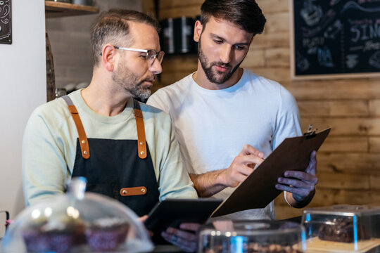 Couple owners bakery working while analyzing report for order delivery with digital tablet in a healthy pastry shop. - Powered by Adobe