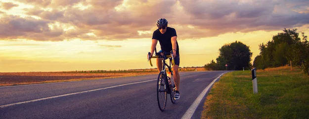 Foto auf Glas Young sports man biker cycling with bicycle on the road in summer © Solid photos