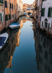Beautiful view of a canal in Venice, Italy around sunset and traditional architecture on the background 